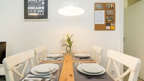 Een eethoek met een houten tafel, witte stoelen en een hangende lamp.