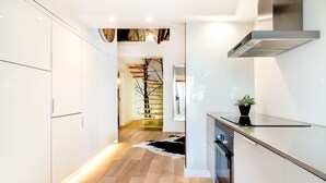 A modern kitchen with white cabinetry, a stainless steel range hood, and a black countertop. - Downtown Luxury Duplex | AC | Elevator | Wi-Fi (Lisboa)