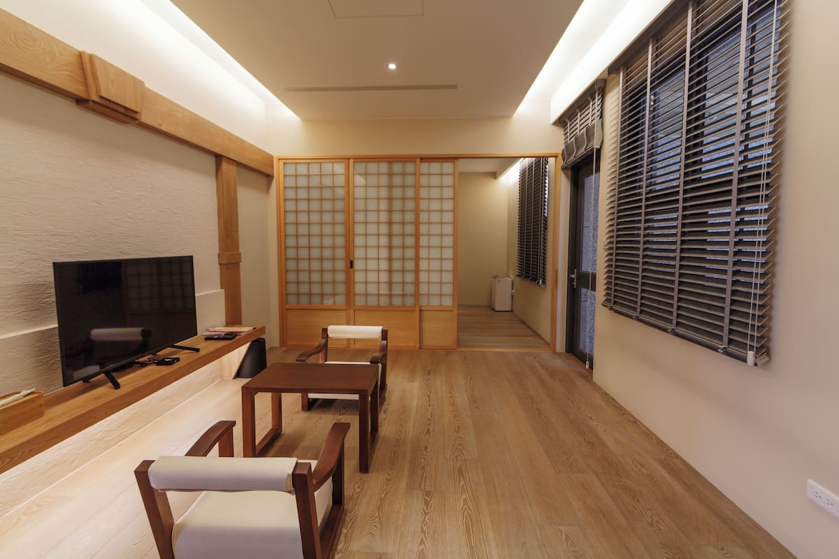 A traditional Japanese-style living room with tatami flooring, a low table, and a television.