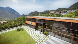 Un edificio moderno con ampie vetrate, tetto piano e terrazza pavimentata con piante in vaso.