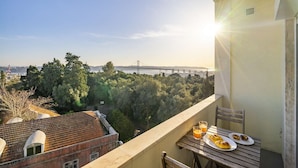 A balcony with a table set for breakfast, overlooking a bridge and a forested area. - Borja111 | Amazing View | AC | Elevator | Families (Lisboa)