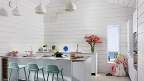 Una cocina moderna con una isla central, taburetes de bar, un ventanal con vistas y un adorno en la pared.