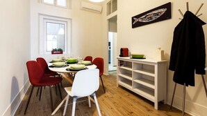 A dining area with a white table, red chairs, and a white shelf unit.