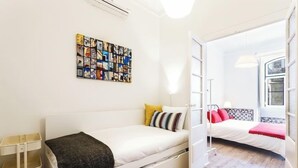 A compact room with two beds, a wall art piece, and a small side table.