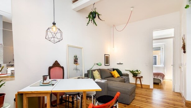 Een moderne woonruimte met een eethoek, een grijze bank en een houten vloer.