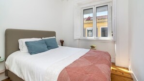 Een slaapkamer met een bed, een raam en een nachtkastje.