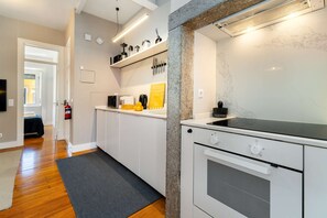 Une cuisine moderne avec des meubles blancs, une plaque de cuisson à induction noire et un four encastré.