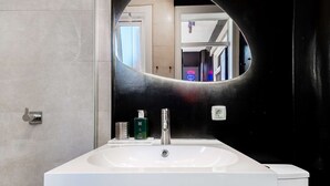 Een badkamer met een wit wastafelmeubel, een spiegel en een zwarte wand.