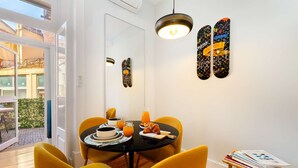 Een eetgedeelte met een ronde tafel, gele stoelen en een moderne hanglamp.
