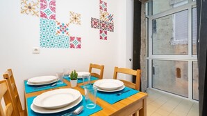 A dining area with a wooden table set for four, blue placemats, and decorative wall art.