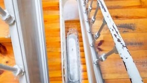 A staircase with a metal handrail and a glass enclosure at the bottom.
