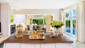 A well-lit living room with a wooden coffee table, a lamp, and a vase with flowers.