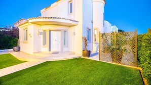 A two-story white house with a curved facade, a small front porch, and a well-maintained lawn.
