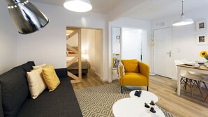 Ett modernt vardagsrum med en soffa, en gul fåtölj och ett vitt soffbord. En trappa leder upp till ett övre plan.