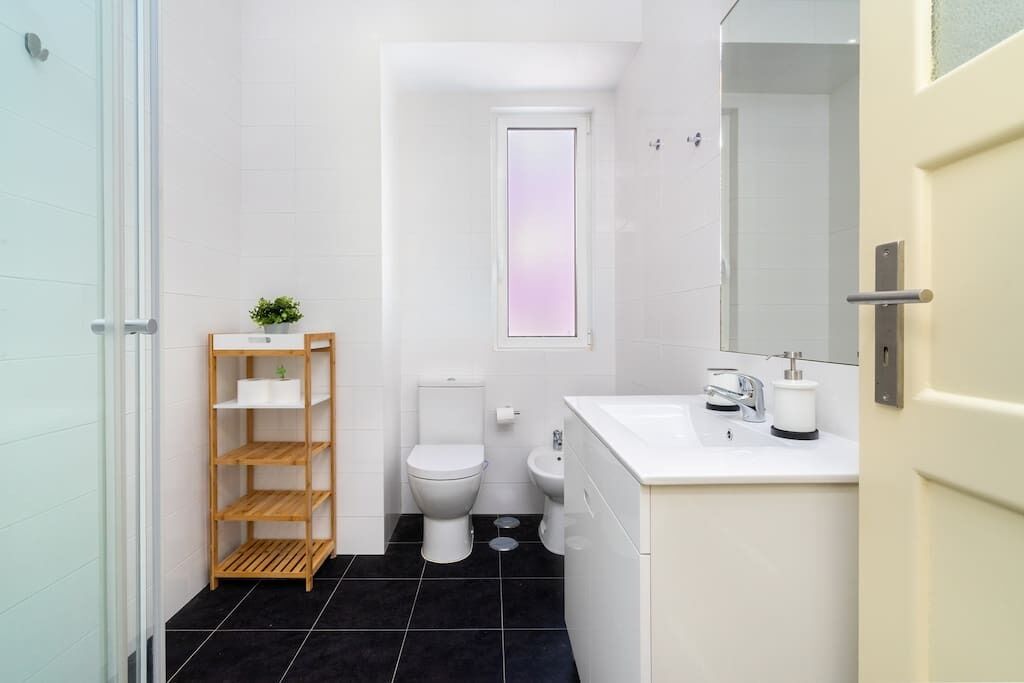 Un baño pequeño con inodoro, bidé y un estante.