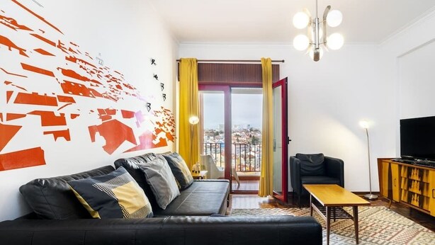 Ein modernes Wohnzimmer mit einem schwarzen Sofa, einem Holztisch und einer TV-Konsole.