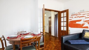 Ein Essbereich mit einem runden Holztisch, gedeckt für vier Personen, einer schwarzen Ledersofa und einer Wand mit einem rot-weißen abstrakten Design.