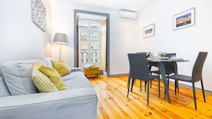 A modern living room with a sofa, a dining table with chairs, and a wooden floor. - Lisbon Prime Aparts - Prata (Lisboa)