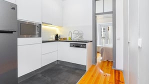 A modern kitchen with white cabinets, a stainless steel refrigerator, a built-in microwave, and a dishwasher. - Lisbon Prime Aparts - Prata (Lisboa)
