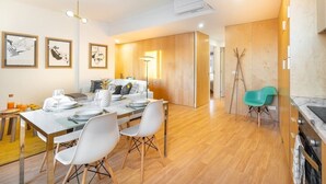 A modern dining area with a wooden table set for four, white chairs, and framed artwork on the wall.