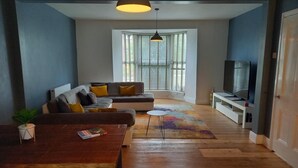 Ein modernes Wohnzimmer mit einer Couch, einem Fernseher und einem Esstisch.