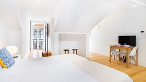 A modern, well-lit room with a bed, a desk, and a television. There is a door leading to another room. - Lisbon Prime Aparts - Baixa (Lisboa)