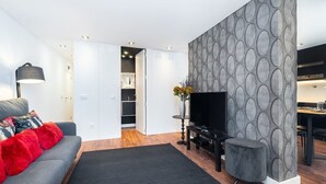 A modern living room with a grey sofa, a black entertainment unit, and a grey accent wall with circular patterns.
