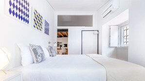 Un dormitorio con una cama grande, paredes blancas y una ventana.
