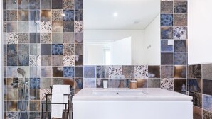 Un baño moderno con un lavamanos grande, una cabina de ducha de vidrio y un salpicadero de azulejos.