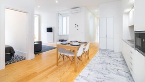 A modern kitchen with white cabinets, a black microwave, and a marble floor. - Lisbon Prime Aparts - Baixa (Lisboa)