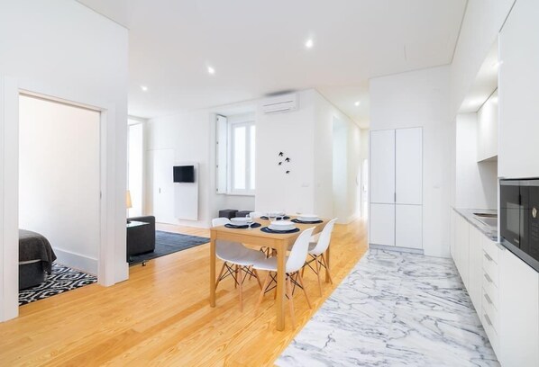 A modern kitchen with white cabinets, a black microwave, and a marble floor.