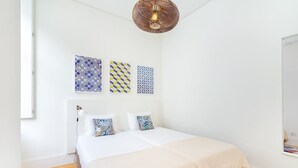 A bedroom with a bed, a hanging light fixture, and three wall-mounted decorative tiles. - Lisbon Prime Aparts - Baixa (Lisboa)