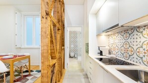 A modern kitchen with white cabinets, a wooden accent wall, and patterned backsplash tiles. - Lisbon Prime Aparts - Baixa (Lisboa)