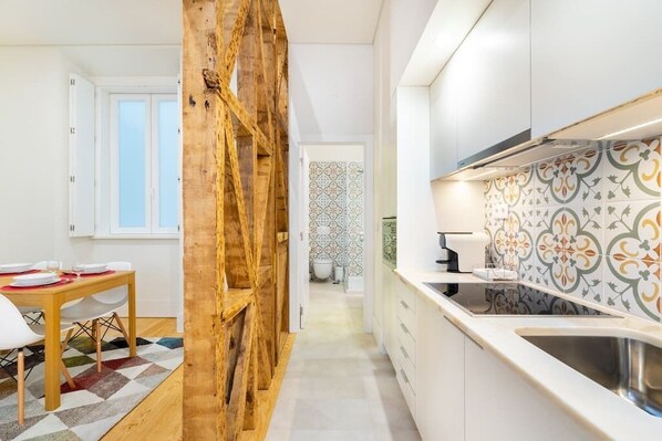 Una cocina moderna con armarios blancos, una pared decorativa de madera y azulejos con estampado.