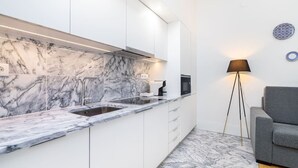 A modern kitchen with white cabinetry, a marble backsplash, and a built-in oven. - Lisbon Prime Aparts - Baixa (Lisboa)