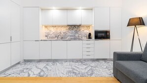 A modern kitchen with white cabinets, a marble backsplash, and a built-in microwave. - Lisbon Prime Aparts - Baixa (Lisboa)
