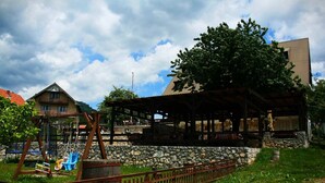 Una estructura de madera rústica con un muro de piedra, un columpio y un área cercada.