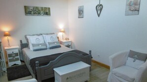 Une chambre à coucher comprenant un lit, des tables de chevet, une commode, une chaise et un banc.