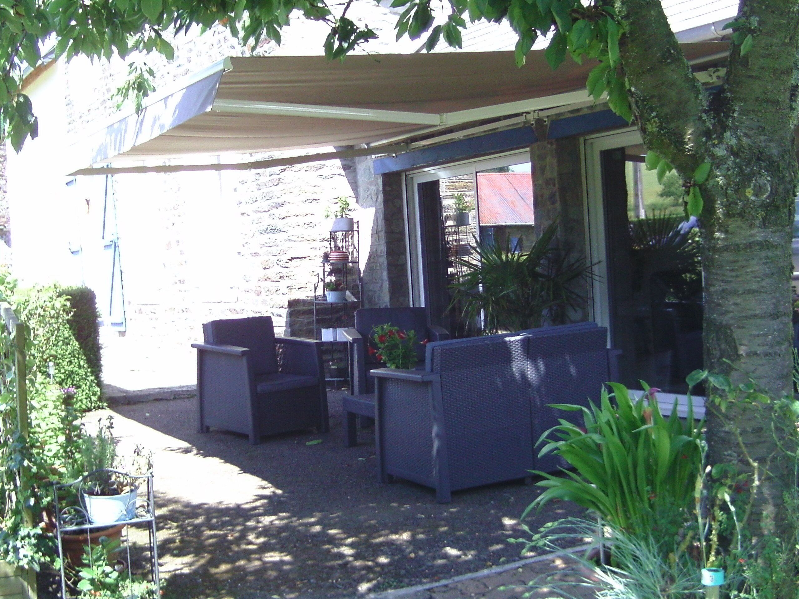 An outdoor patio area with wicker furniture, potted plants, and a stone wall.