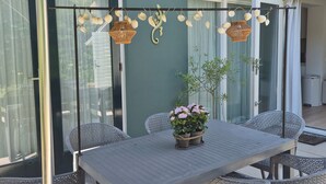 Un patio al aire libre con una mesa, sillas, un colgante de luz y una planta en maceta.
