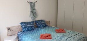 A bed with blue patterned bedding, two pillows with star designs, and a macrame wall hanging. - Ruim vakantiehuis voor 4 personen, sauna, 2 badkamers vlakbij het strand.  (Den Haag)