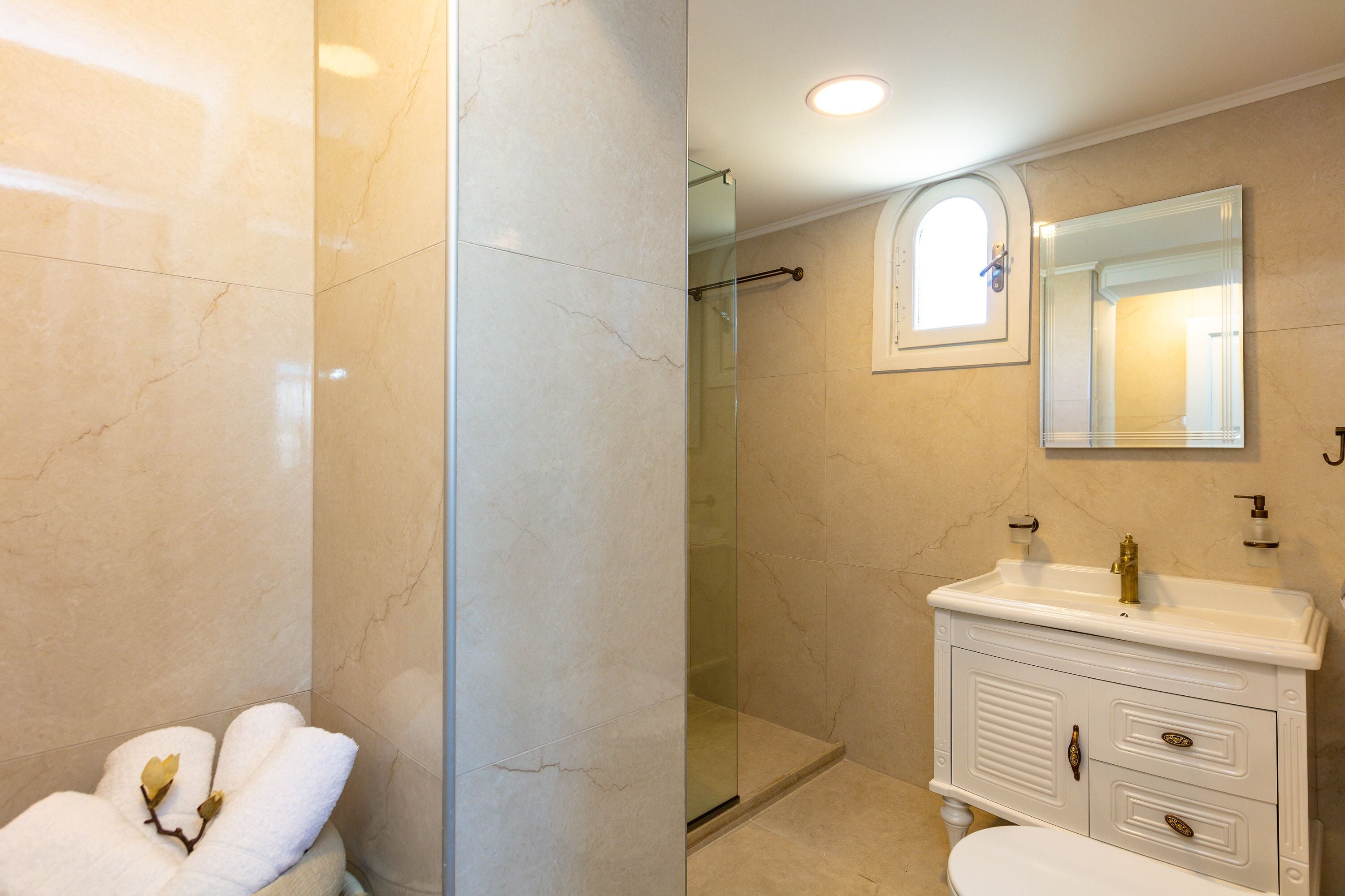 A bathroom with a glass-enclosed shower, a white vanity with a mirror, and a toilet.
