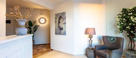 Una sala de estar moderna con un sillón gris, una mesa redonda y un espejo grande.