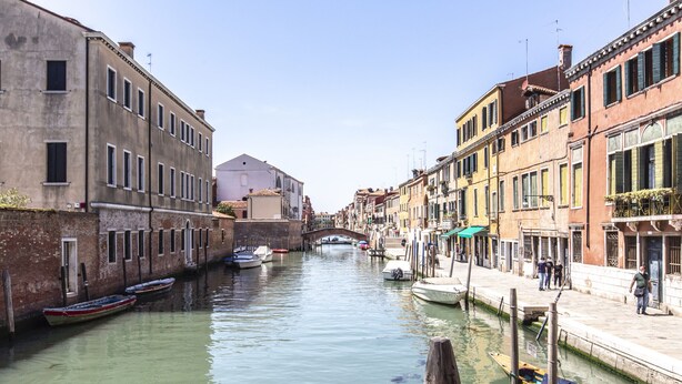 Un canale con barche, edifici storici e un ponte.
