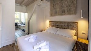 Camera da letto con un letto grande, una testiera in legno e un elemento decorativo a parete. Si vede una scala che conduce a un'altra stanza.