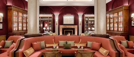 A library with a red sofa, wooden chairs, and bookshelves.