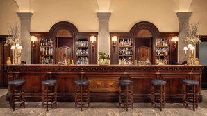 A bar area with a long counter, multiple stools, and a variety of bottles and glasses. - Tivoli Palazzo Gaddi Firenze Hotel (Florence)