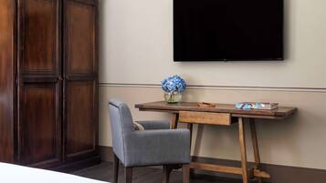 Una camera d'albergo con una scrivania in legno, una sedia, una TV a schermo piatto e un armadio.