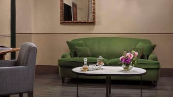 Un canapé vert, un vase de fleurs, une table basse et un miroir au mur.