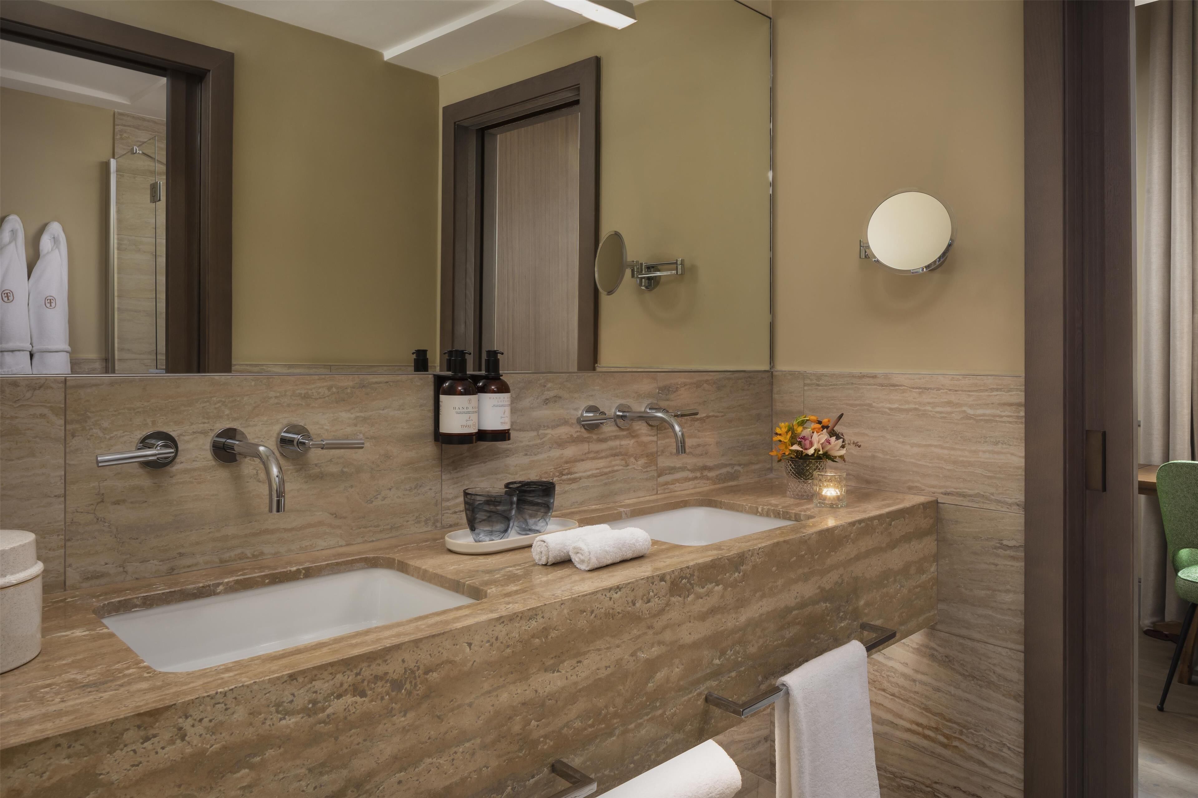 Un bagno con due lavandini, uno specchio grande e un porta asciugamani.
